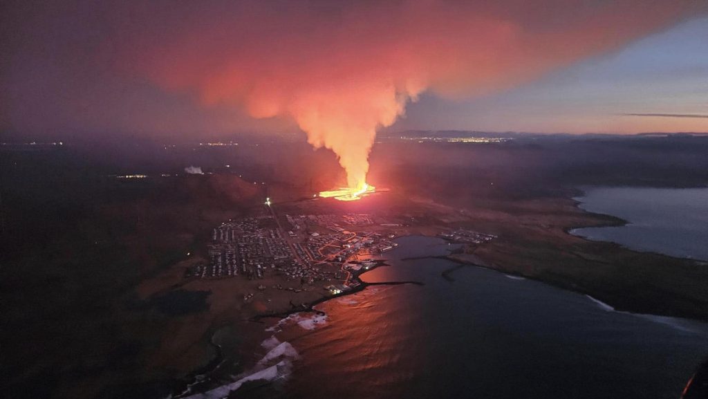 Orange lava flowing towards a fishing village with massive ash cloude rising up from the craters.